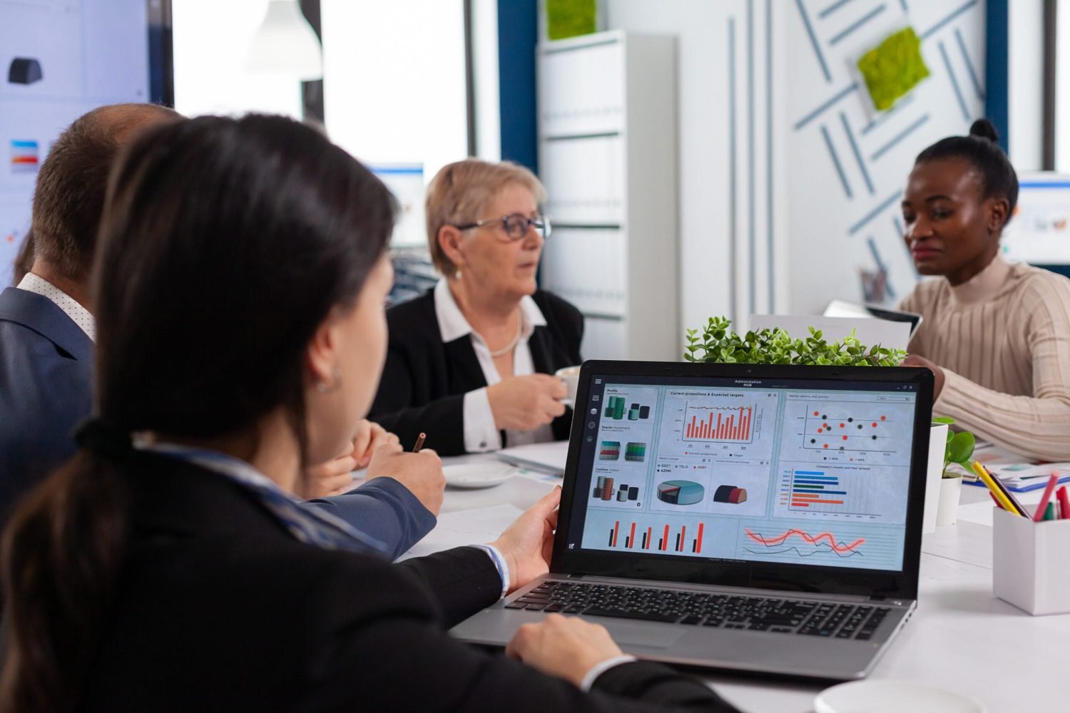 Young woman analysing charts on laptop in business meeting room Young woman analysing charts on laptop in start up business meeting room. Multiethnic coworkers breefing team diverse people leadership. African employee listening senior manager.